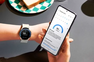 Galaxy Watch 5 en una muñeca mostrando su pantalla activa con métricas de salud como ritmo cardíaco y pasos, en un entorno al aire libre.