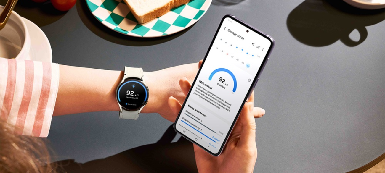 Galaxy Watch 5 en una muñeca mostrando su pantalla activa con métricas de salud como ritmo cardíaco y pasos, en un entorno al aire libre.